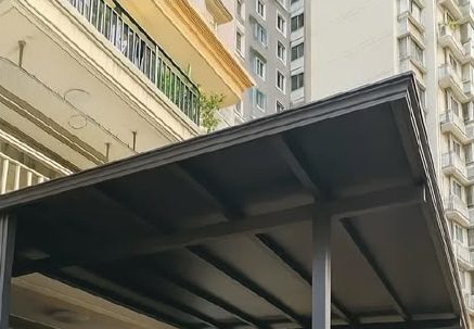 Metal awning frame seen from below, next to a high-rise residential block