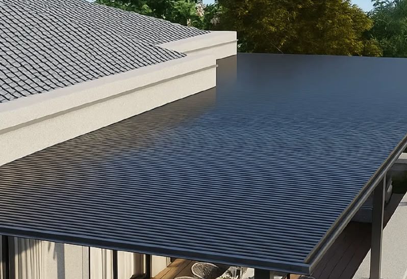 Ribbed-panel awning extending from a roofline over an outdoor terrace